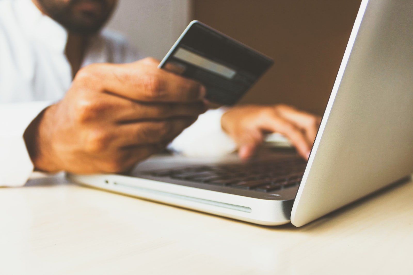 person using laptop computer holding card for transfer money